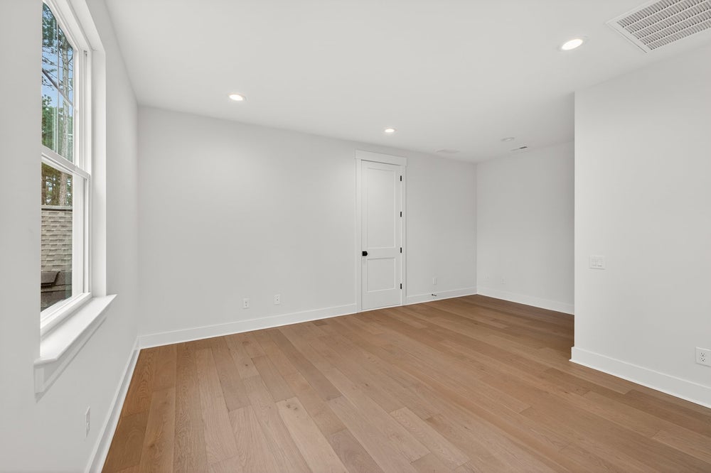 Empty room with white walls, light hardwood floors, and recessed lighting