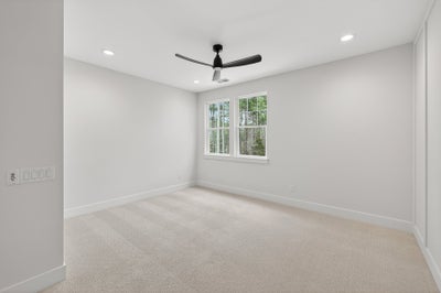 Empty bedroom with beige carpet, white walls, ceiling fan, and double window