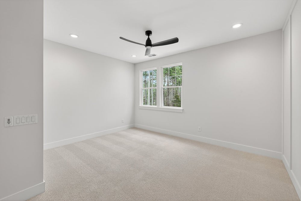 Empty bedroom with beige carpet, white walls, ceiling fan, and double window