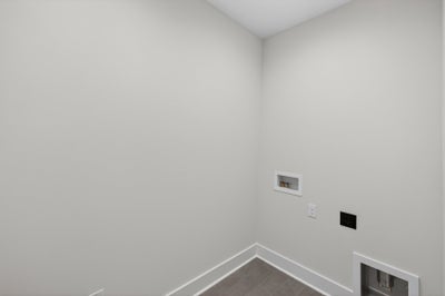 Empty room with white walls and gray tile flooring with electrical outlets