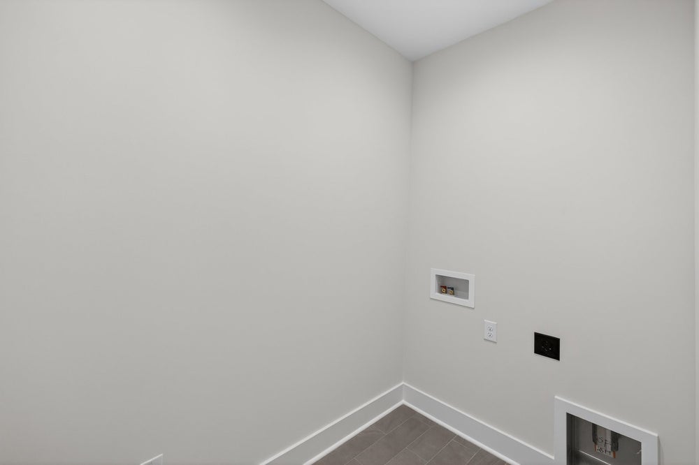 Empty room with white walls and gray tile flooring with electrical outlets