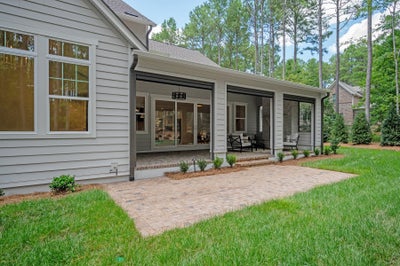 Covered patio with screened enclosure, brick pavers, and gray siding exterior