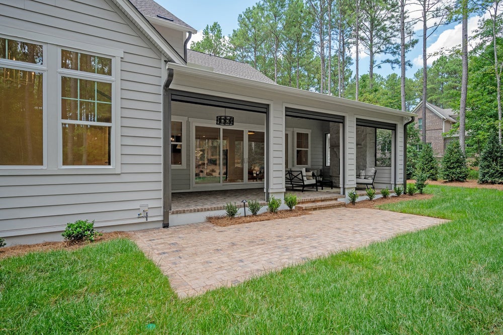 Covered patio with screened enclosure, brick pavers, and gray siding exterior