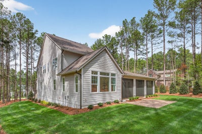 Two-story home with gray siding, two-car garage, and wooded lot