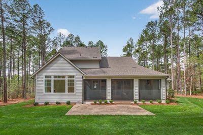 Single-story home with gray siding, three-car garage, and wooded lot