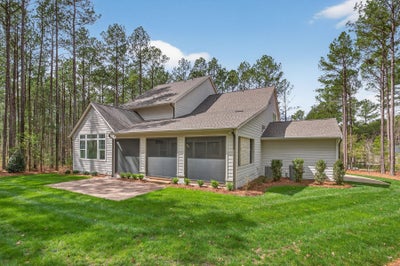 Single-story home with gray siding, three-car garage, and wooded lot
