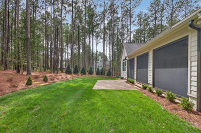 Two-car garage with gray doors and landscaped yard surrounded by pine trees