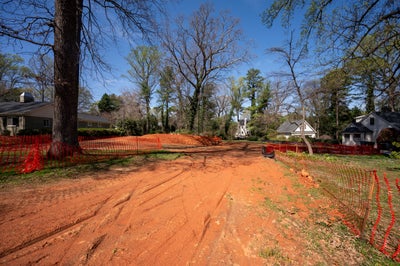 Residential construction site with cleared dirt lot and orange safety fencing