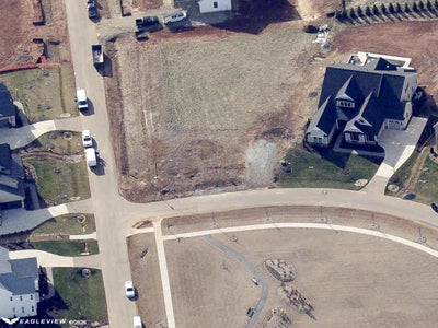 Aerial view of vacant residential lot in subdivision with paved streets and nearby homes