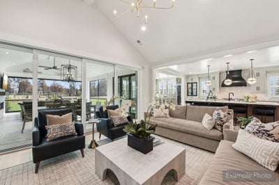 Open-concept living room with vaulted ceiling, sliding glass doors, and kitchen visible in background