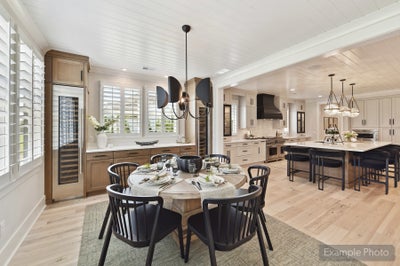 Open dining area with round wood table flowing into kitchen with large island and hardwood floors
