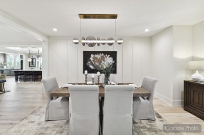 Formal dining room with wood table, upholstered chairs, globe pendant light, and white shiplap accent wall