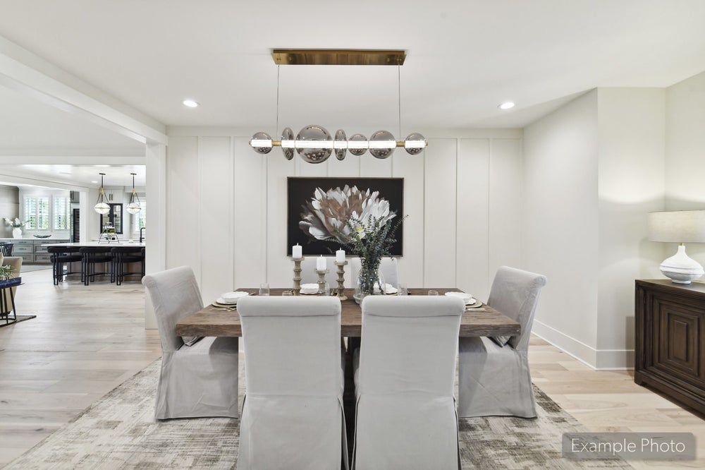 Formal dining room with wood table, upholstered chairs, globe pendant light, and white shiplap accent wall
