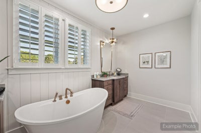 Bathroom with freestanding soaking tub, dark wood vanity, plantation shutters, and decorative pendant light fixture
