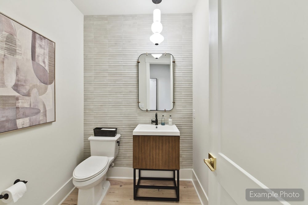 Powder room with wood vanity, textured tile accent wall, pendant light, and framed mirror