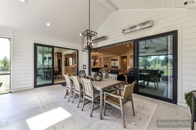 Covered outdoor patio with dining table, vaulted shiplap ceiling, and sliding glass doors leading inside