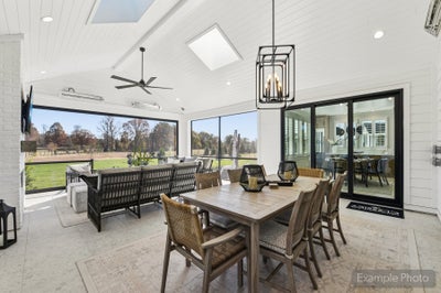 Screened porch with vaulted shiplap ceiling, dining table, ceiling fan, and views of a grassy backyard