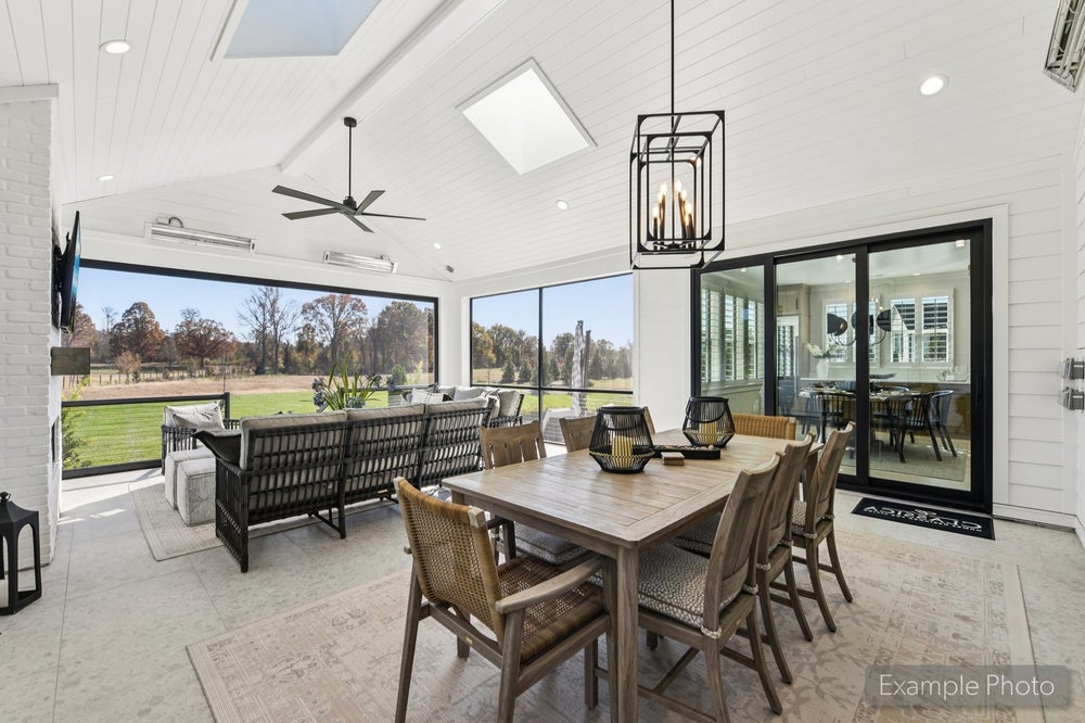 Screened porch with vaulted shiplap ceiling, dining table, ceiling fan, and views of a grassy backyard