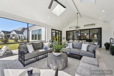 Screened porch with vaulted ceiling, gray sectional seating, skylight, and views of backyard and neighborhood