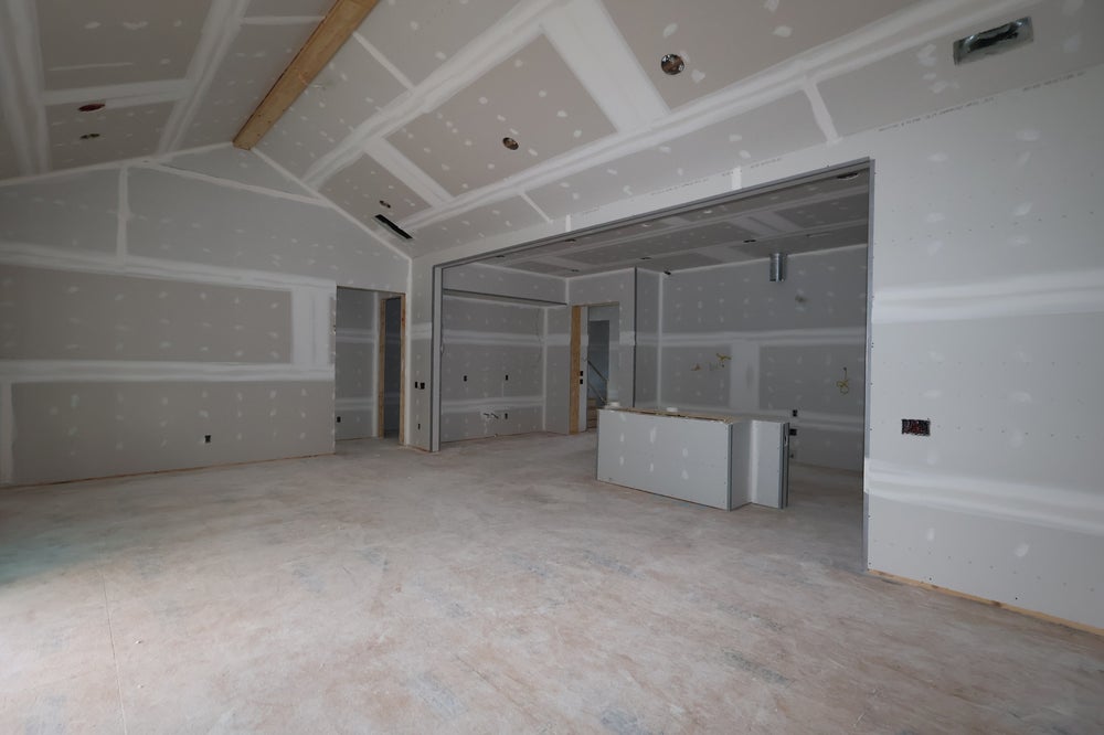 Unfinished basement with drywall installation and coffered ceiling under construction