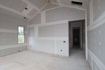 Empty room under construction with drywall, coffered ceiling, and window
