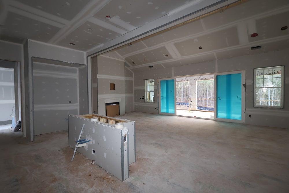 Open-concept living space under construction with coffered ceiling and sliding glass doors
