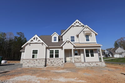 New two-story craftsman home with white siding, stone foundation, and covered front porch under construction