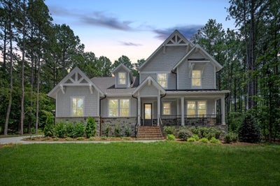 Two-story craftsman home with gray siding, stone accents, and covered front porch
