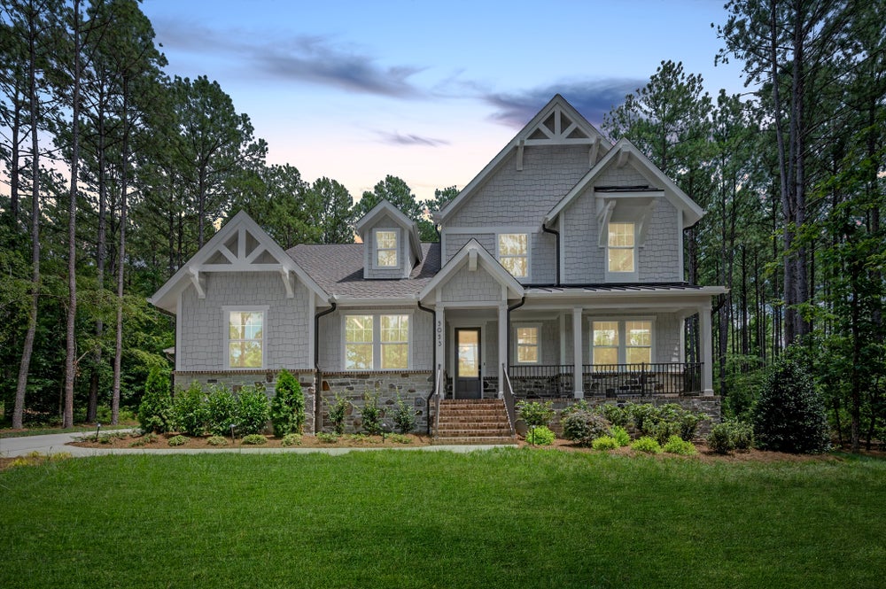 Two-story craftsman home with gray siding, stone accents, and covered front porch