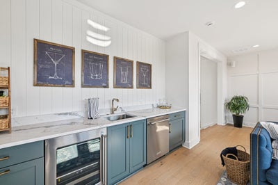 Wet bar with blue-gray cabinets, marble countertops, and stainless steel appliances