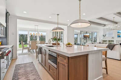 Open-concept kitchen with large island, pendant lights, and view to dining and living areas