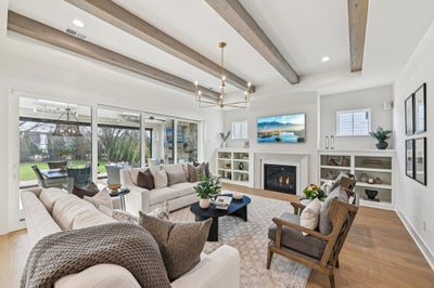 Living room with exposed wood beams, fireplace, built-in shelving, and sliding glass doors to backyard