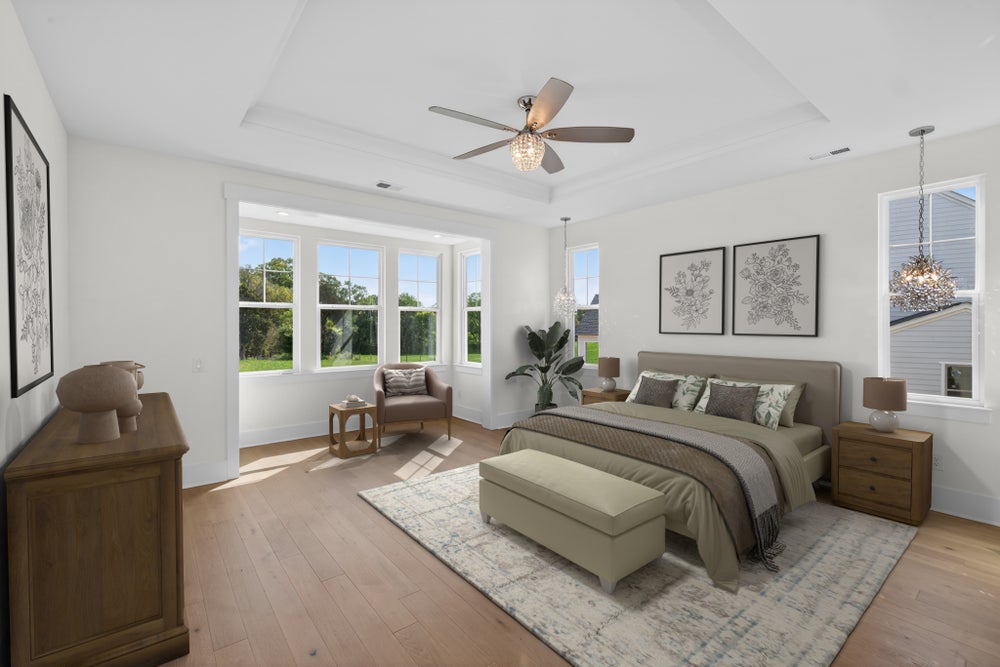 Spacious master bedroom with hardwood floors, bay windows, ceiling fan, and neutral furnishings including a king bed and sitting area.