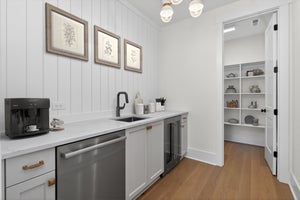 Butler's pantry with white shiplap walls, stainless appliances, sink, and open shelving in adjacent walk-in pantry