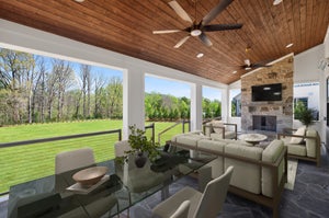 Covered porch with wood ceiling, stone fireplace, ceiling fan, seating area, and backyard views
