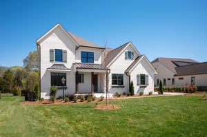 Two-story white brick home with covered entry, gray shutters, and well-maintained front lawn