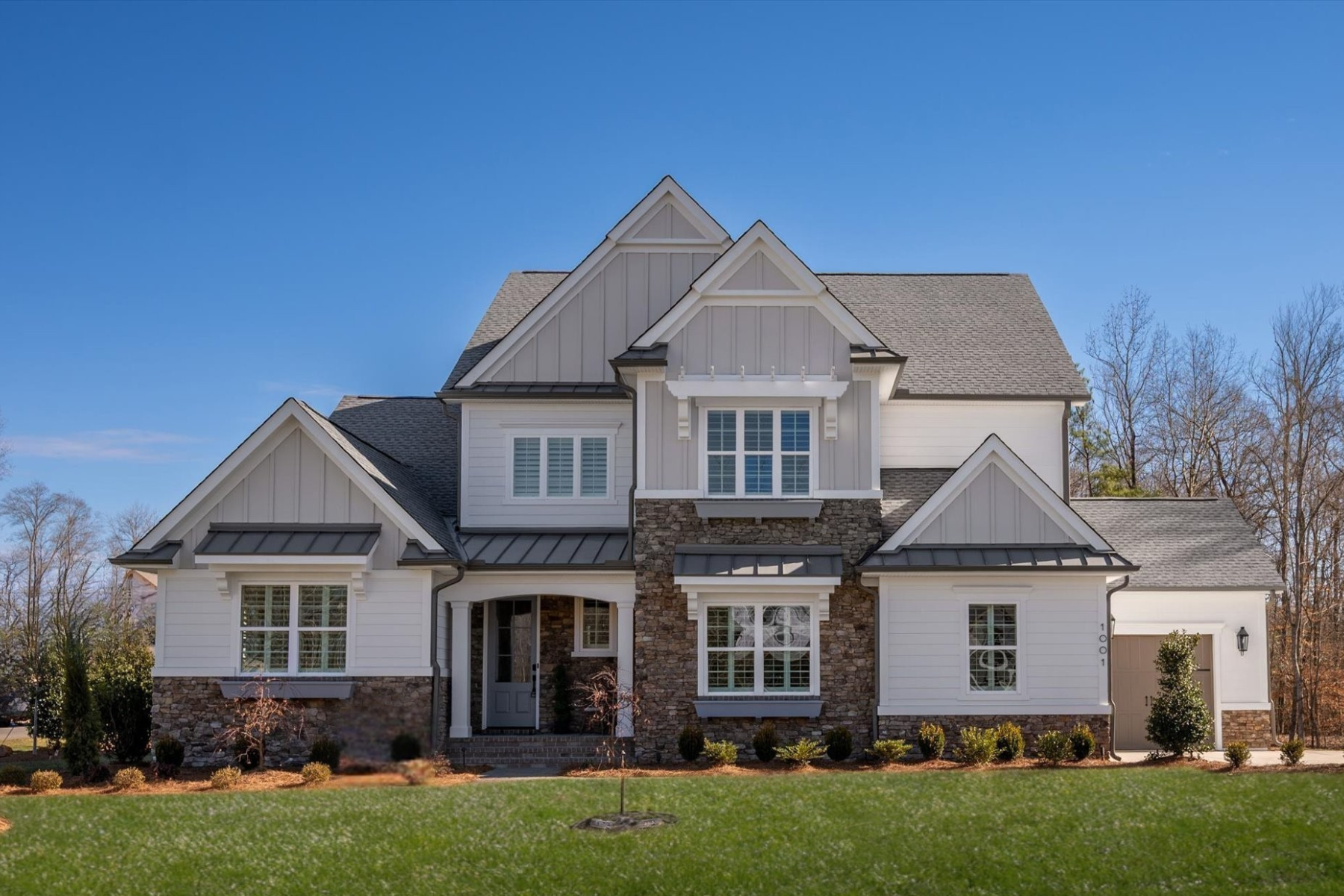 Two-story craftsman home with white board-and-batten siding, stone accents, and a covered front entry