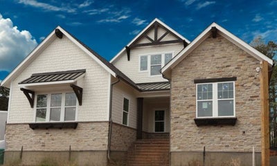 New construction home with stone and white brick exterior, metal roof, and decorative wood accents over windows