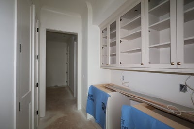 Hallway and butler's pantry under construction with white glass-front cabinets and protected countertops