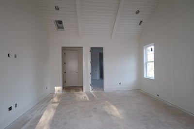 Empty bedroom with vaulted shiplap ceiling, two doorways, and a single window during construction