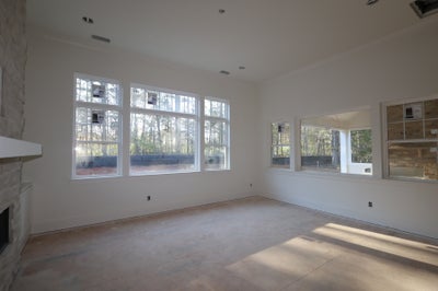 Unfinished living room with stone fireplace, large windows, and bare concrete floors under construction