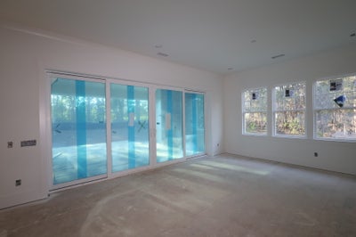 Unfinished room with large sliding glass doors and side windows, concrete floor, white drywall walls under construction