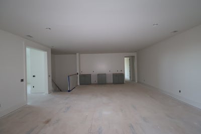 Unfinished open room under construction with gray base cabinets, bare floors, and recessed ceiling lights