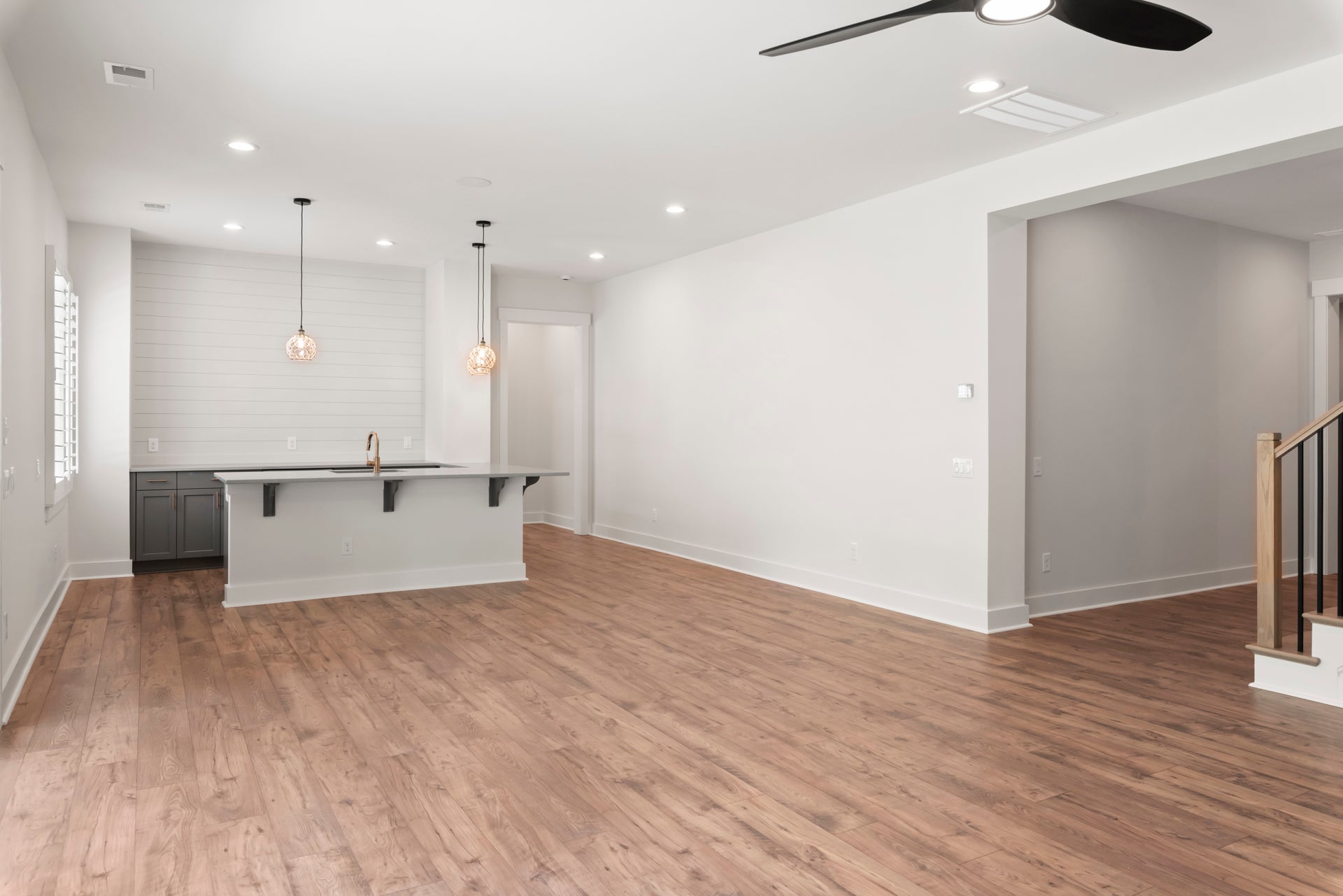 Open living area with hardwood floors, kitchen island, pendant lights, and ceiling fan