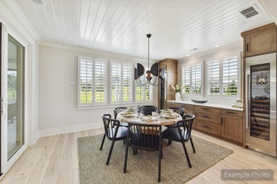 Dining area with round table, black chairs, shiplap ceiling, plantation shutters, and wood cabinetry with wine fridge nearby.