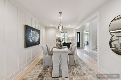 Formal dining room with wood table, upholstered chairs, board-and-batten walls, and pendant light over area rug