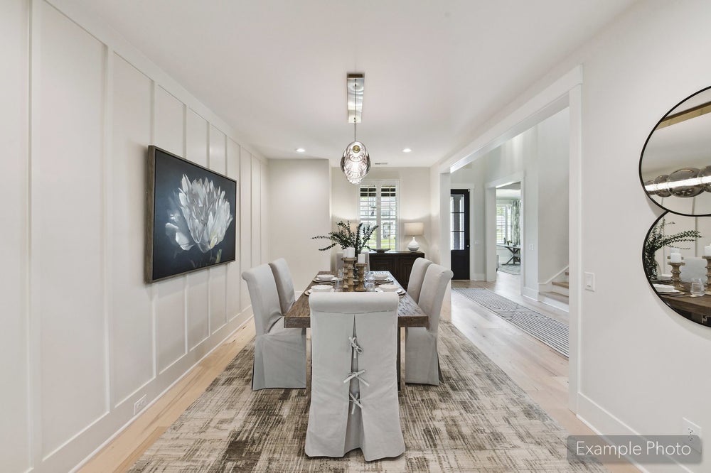 Formal dining room with wood table, upholstered chairs, board-and-batten walls, and pendant light over area rug