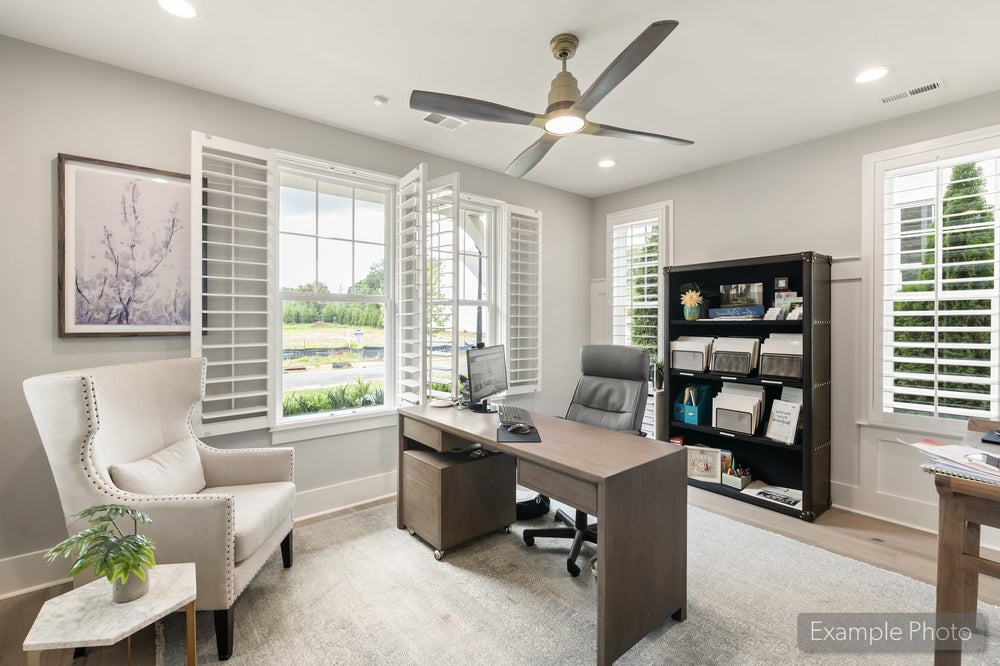 Home office with wood desk, ceiling fan, plantation shutters, and built-in bookshelf