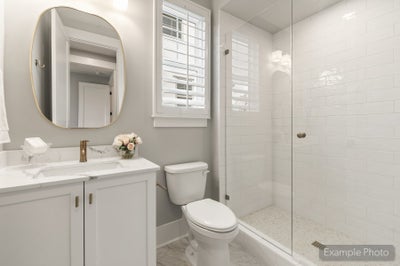 Bathroom with white vanity, marble countertop, glass walk-in shower, and subway tile walls