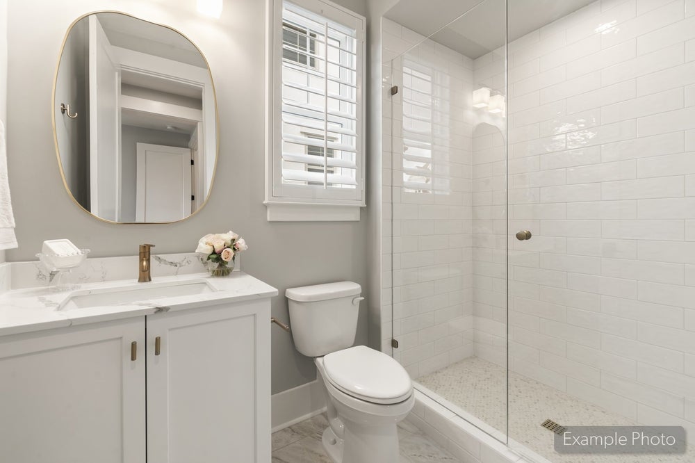 Bathroom with white vanity, marble countertop, glass walk-in shower, and subway tile walls